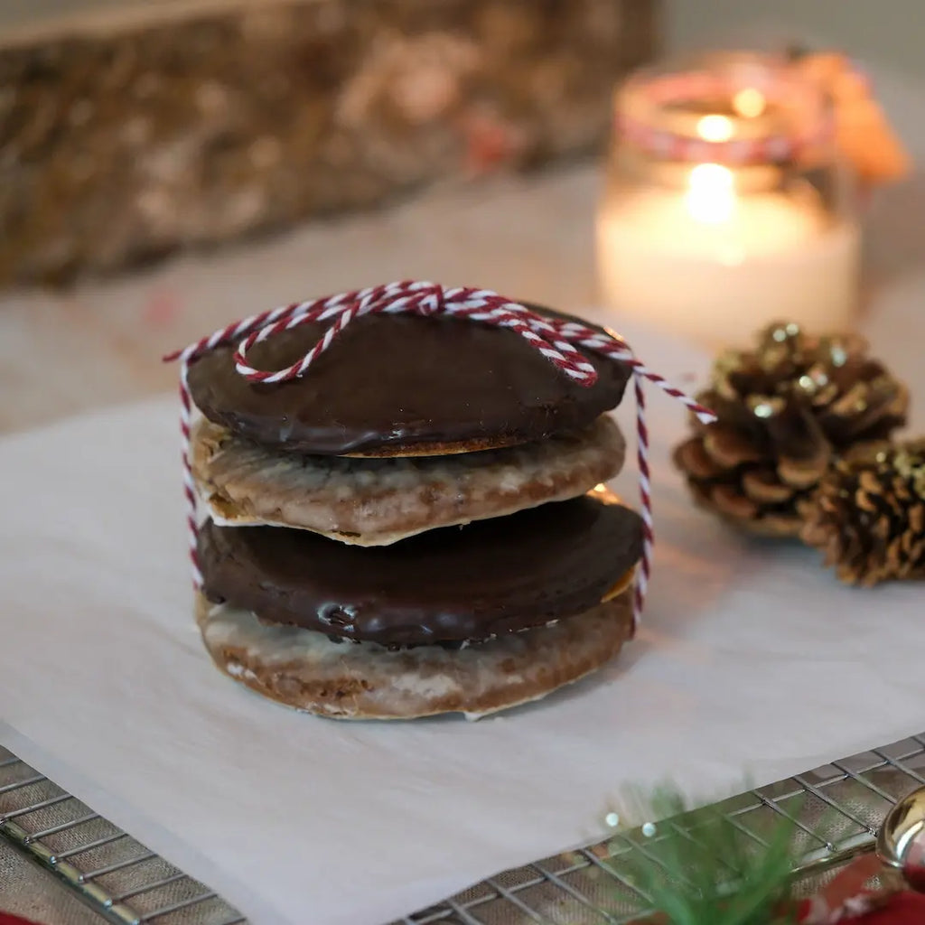 vier Elisenlebkuchen mit Schokoglasur und Zuckerglasur gestapelt mit Geschenkband