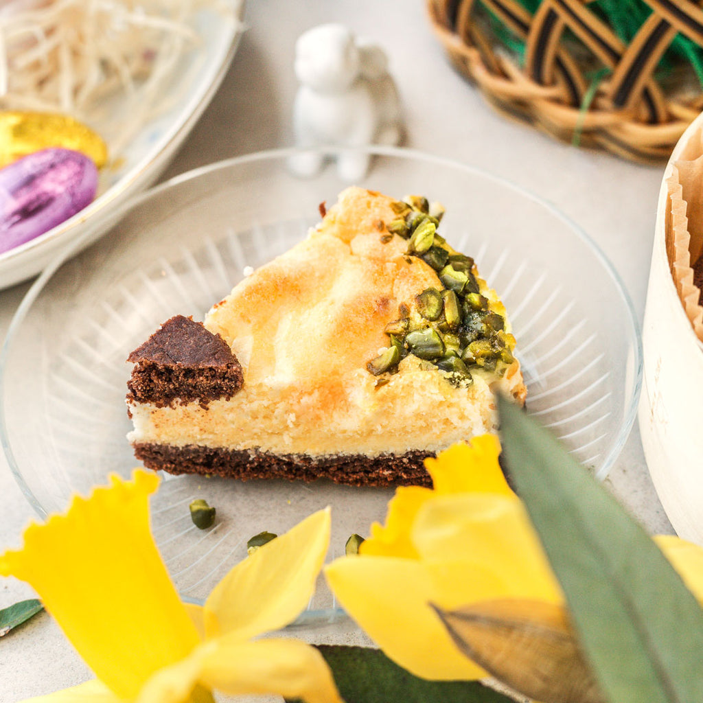 Ein Stück Oster Zupfkuchen von Oma Monika auf einem Teller, umgeben von Blumen und Osterdeko